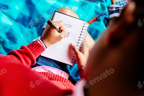 Preview: High angle view of university student writing in diary at park