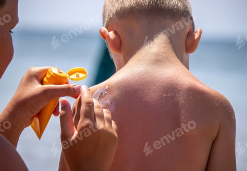 Preview: Mother puts cream on her son's back. Caring for baby skin. Sunscreens in the travel
