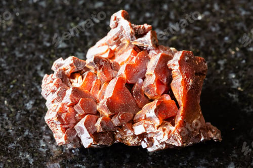 Preview: sample of raw vanadinite crystals on black granite