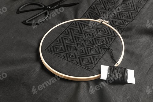 Preview: Embroidery hoop, thread and scissors on black shirt. Ukrainian national clothes