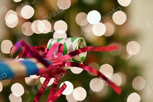 Preview: Happy New Year! noisemaker, horn blower in front of some holiday Christmas lights