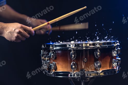Preview: Drum sticks hitting snare drum with splashing water on black background.