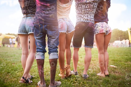 Preview: Group of friends at festival, covered in colourful powder paint, low section, rear view
