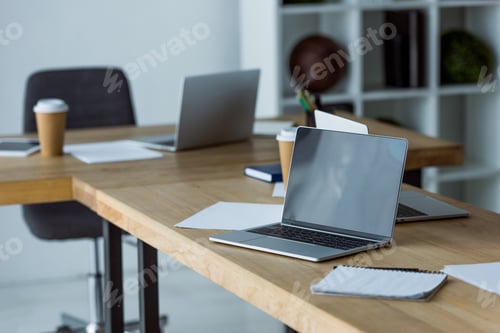 Preview: laptops and coffee in paper cups on table in start up office