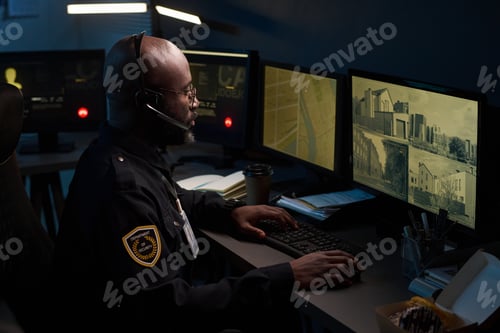 Preview: Black Man Monitoring Security Cameras in Surveillance Control Room