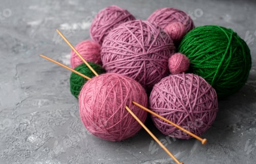 Preview: Different size pink, purple and green balls of yarn with wooden knitting needles