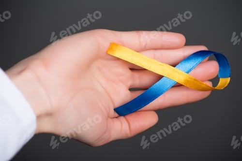 Preview: Female hand with Down Syndrome Day ribbon isolated on grey
