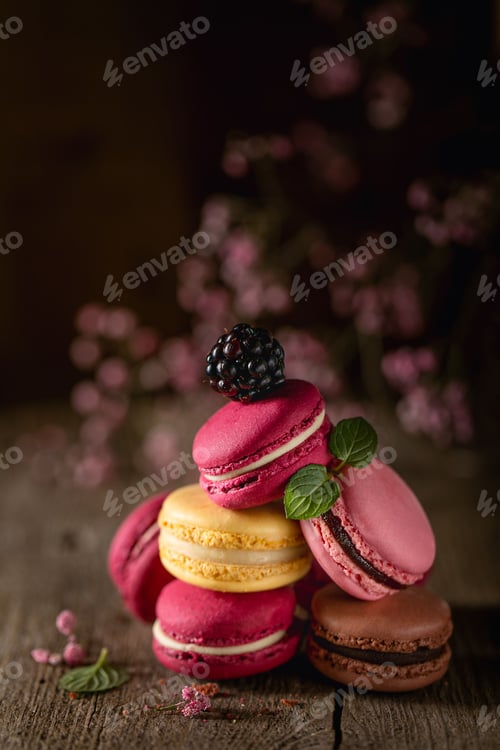 Preview: Colorful macarons with a blackberry on rustic wood.