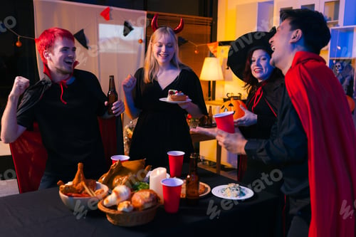 Preview: Dinner and group of people celebrating together at Halloween party.