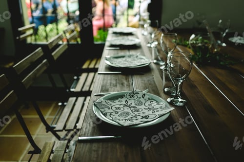Preview: Wooden tables with cutlery plates and backlit glasses without anyone.
