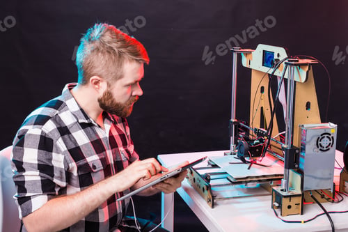 Preview: Technology and engineering concept - Male engineer working at night in the lab, he is adjusting a 3D