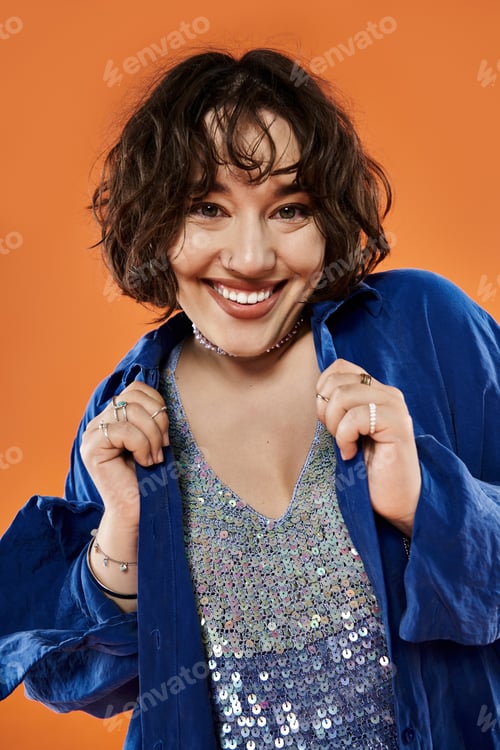 Preview: Joyful Woman in Blue Against a Vivid Orange Backdrop