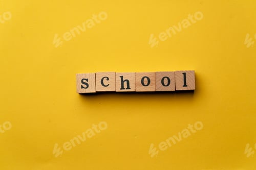 Preview: a yellow warm background without shadows wooden cubes with black letters laid out word school