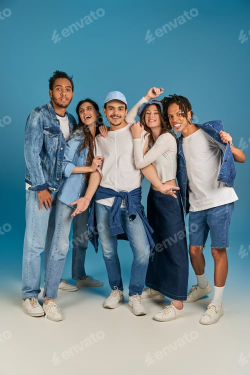 Preview: group portrait of interracial friends in trendy and denim clothes on blue backdrop, full length