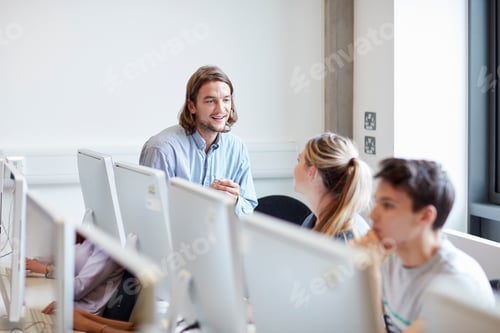 Preview: Male lecturer talking to student in higher education college computer room