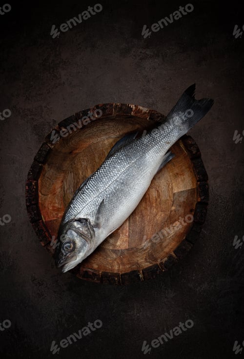 Preview: fresh, raw sea bass fish, in a wooden plate, top view, no people.