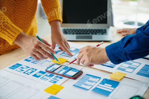 Preview: View of UI developer team brainstorming on their project with laptop, smartphone and digital tablet.