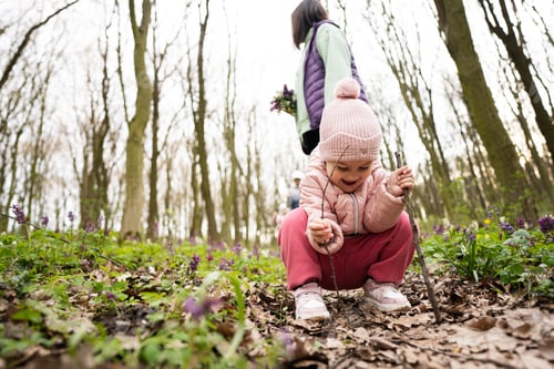 Preview: Baby girl playing with sticks in spring forest.