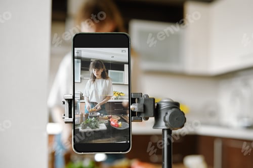 Preview: Woman recording video recipe while cooking in the kitchen