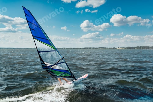 Preview: the athlete rides the windsurf over the waves on the lake
