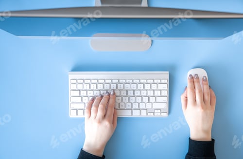 Preview: Top view, female hands work at the computer, blue background.