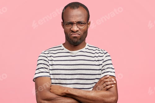 Vista previa: Horizontal shot of discontent African American male model with dissatisfied expression, frowns face