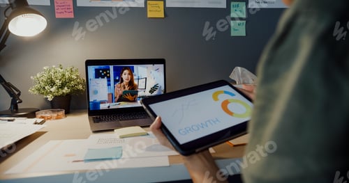 Preview: Asia businesswoman using laptop talk to colleagues about plan in video call meeting at living room.