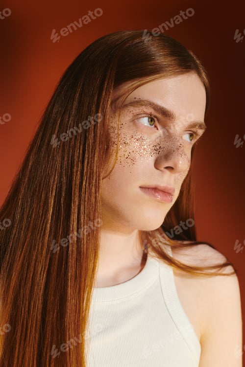 Preview: Stylish young queer man with long red hair embracing modern fashion in warm lighting
