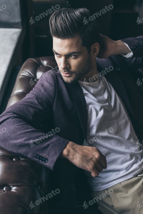 Preview: Portrait of handsome caucasian man with fashionable hairstyle at barber shop