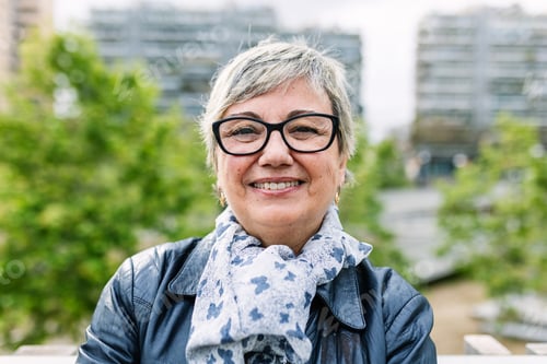 Preview: Smiling portrait of senior woman looking at camera outdoor