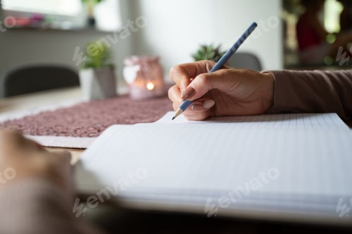 Preview: Woman writing in blank notebook on wooden desk