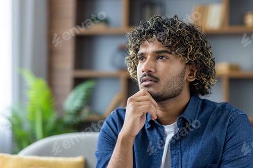 Preview: Serious thinking man close up, looking intently out the window at home, pensive in the living room