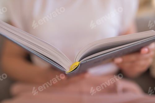 Vista previa: A woman reading a book on the sofa.