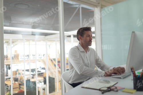 Preview: Side view of Caucasian business male executive working on computer at desk in a modern office