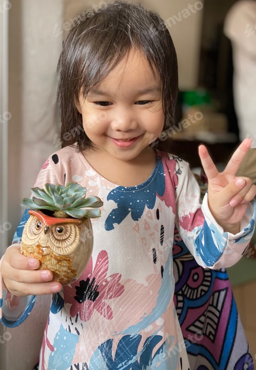 Preview: Happy little girl posing with an owl pot of succulent during Eid celebration