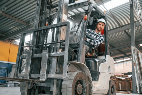 Preview: Inside of the forklift. Factory male worker in uniform is indoors