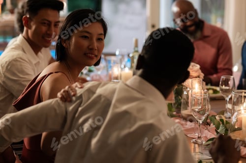 Visualização: Convidados desfrutando de uma conversa animada na elegante mesa de jantar de casamento com velas