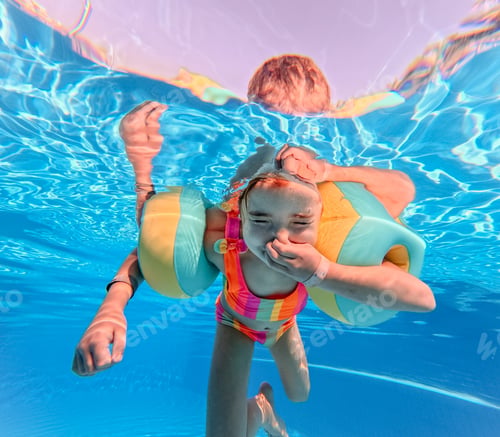 Preview: Little girl in swimsuit diving in swimming pool.