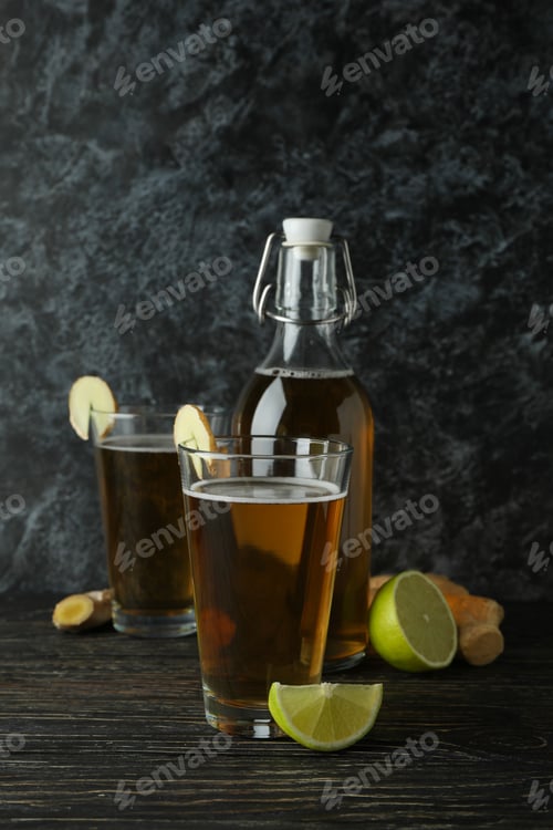 Preview: Concept of delicious drink with glasses and bottle of ginger beer on wooden table