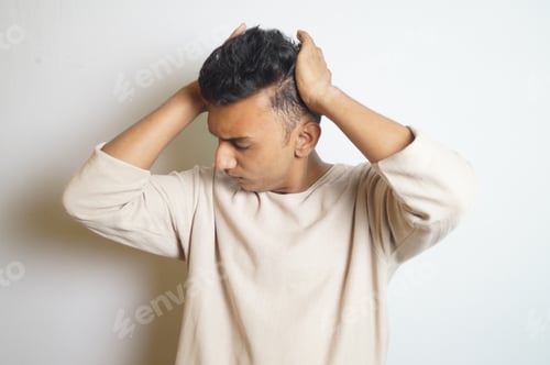 Preview: Young Indian man holding his head with eyes closed