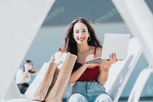 Preview: Young african woman using laptop computer for shopping outdoors with copy space.
