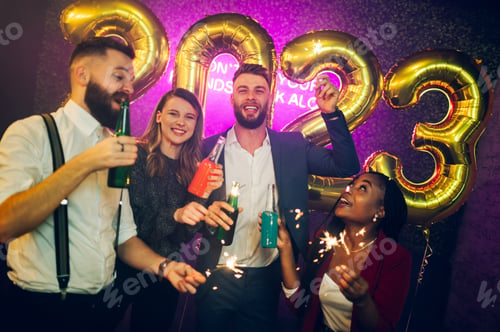 Preview: Multiracial people with sparklers and drinks celebrating new years eve in the club