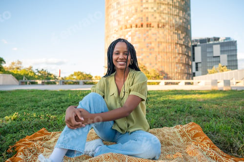 Preview: Young black woman relaxing in Barcelona enjoying summer sun with Torre Glòries in background
