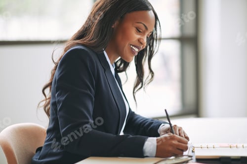 Preview: Smiling African American businesswoman writing notes in her day planner