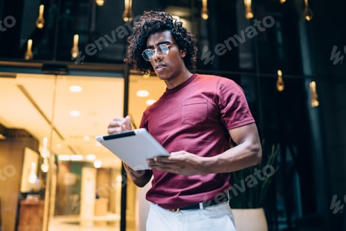 Preview: Cool black man with tablet in hall of modern building