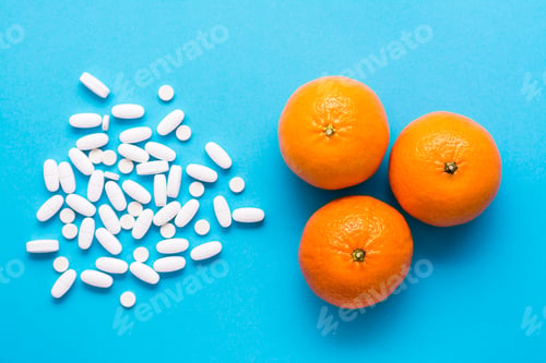 Preview: White large oval pills and ripe oranges on a blue background. Medicines and synthetic vitamins