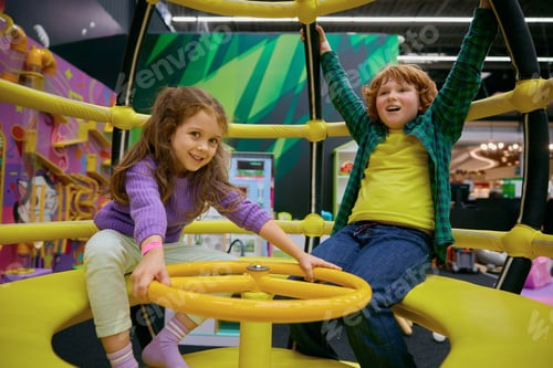 Preview: Happy excited children playing on indoor carousel at play center