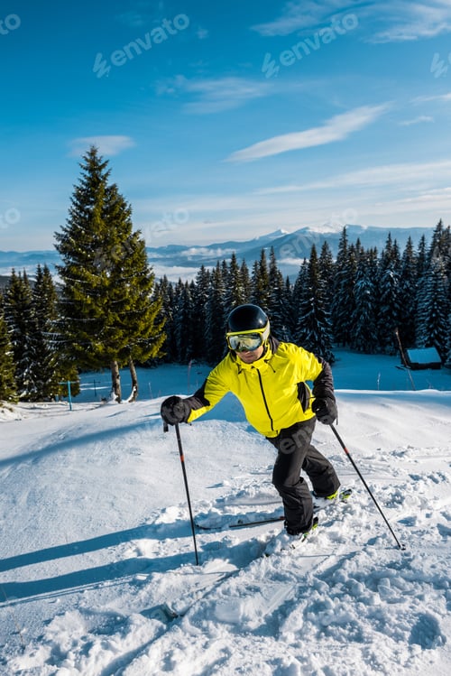 Preview: skier in helmet walking on snow near firs