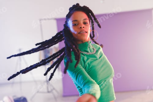 Preview: African American woman moving toward camera in studio, with studio light and purple backdrop