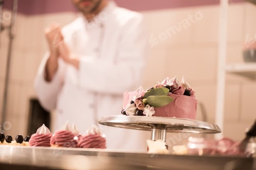 Preview: selective focus of cake, cupcakes and confectioner in restaurant kitchen